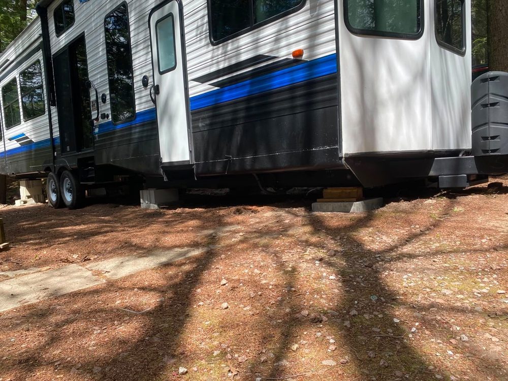 Low view of a park model trailer raised on blocking with the axles and underside visible